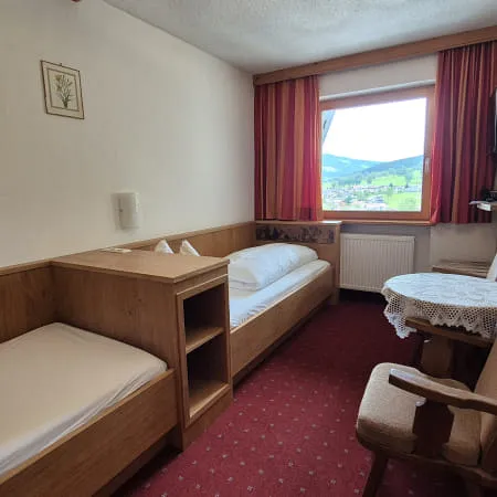 Ein Hotelzimmer mit zwei Betten, einem Tisch und einem Fenster mit Aussicht.