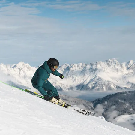 Skifahrer auf einer Piste mit Bergen im Hintergrund