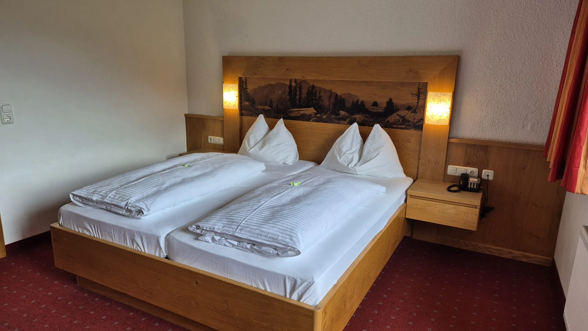 Doppelbettzimmer mit Holzbetten und Kunstwerk an der Wand