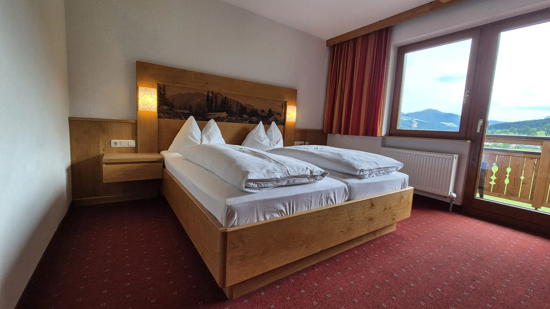 Helles Hotelzimmer mit Holzdetails und Balkonblick.